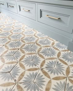 a bathroom with blue cabinets and white countertops, an ornate tile floor design in the middle