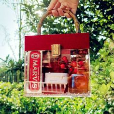 a person holding a red bag with perfumes in it