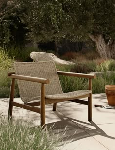 a wooden chair sitting on top of a cement floor next to a potted plant