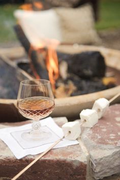 a glass of wine sitting next to a fire pit