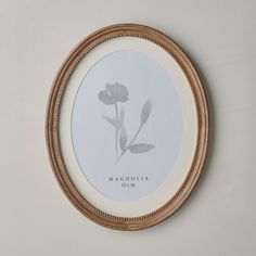 a white and gold framed artwork with a flower in the center on a beige wall