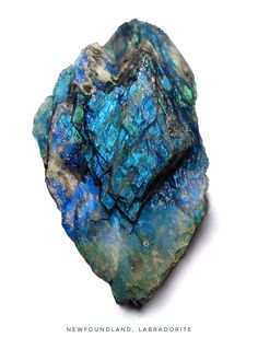 a rock with blue and green crystals on it's side, against a white background