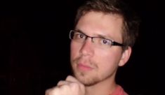 a man with glasses is looking at the camera while holding his hand to his chin