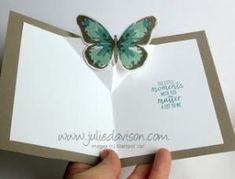 a hand holding an open greeting card with a butterfly on the front and back of it