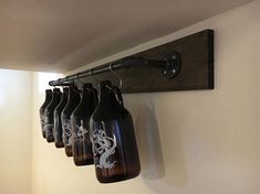 a row of beer bottles hanging from a wooden rack on the wall next to a light fixture