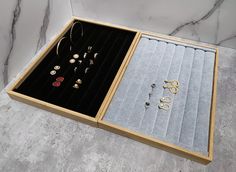 an open jewelry box with several pairs of earrings in it on a marble countertop