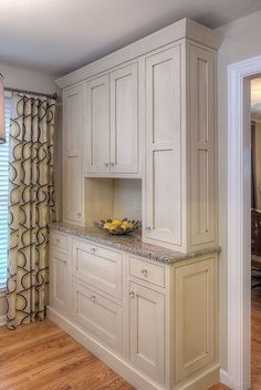 a kitchen with white cabinets and marble counter tops