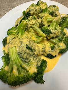 broccoli covered in yellow sauce on a white plate