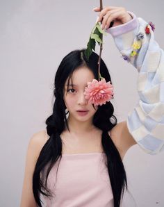 a girl with long black hair holding a flower on her head