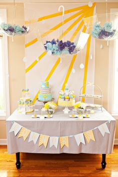 a table topped with cake and cupcakes next to two umbrellas hanging from the ceiling