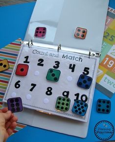 a child's hand is holding a board with numbers and dices on it