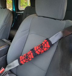 the seat belt is decorated with red and black crocheted designs on it's side