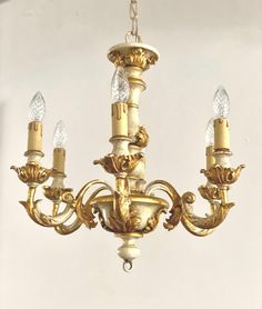 an antique chandelier with five lights hanging from it's center, in a white room