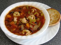 a white bowl filled with soup next to a slice of bread