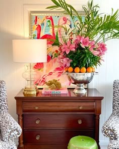 a table with two chairs and a vase filled with flowers on top of it next to a lamp