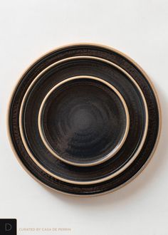 three black and gold plates stacked on top of each other in the shape of circles