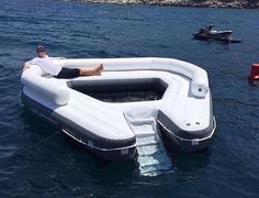 a man laying on top of an inflatable raft floating on the water next to a boat