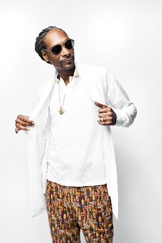 a man wearing sunglasses and a white shirt is posing for the camera with his hand on his hip