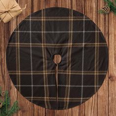 a black and brown plaid pattern on a round tablecloth with pine cones, firs and twine needles