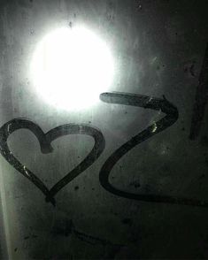 two hearts drawn on the side of a glass door with light shining through it and in the background