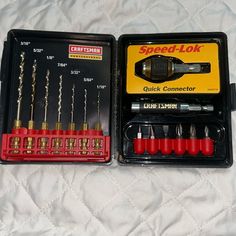 an assortment of tools in a box on a bed