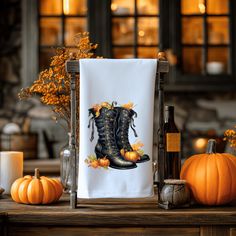 a kitchen towel with a pair of boots on it and pumpkins in the background