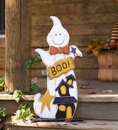 a wooden sign that says boo is on the steps next to some flowers and potted plants