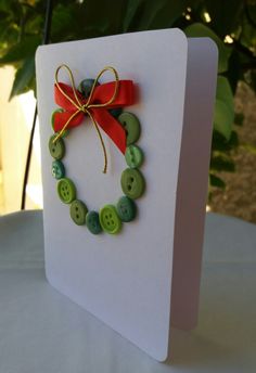 a card with buttons and a red bow on it sitting on a table next to a potted plant