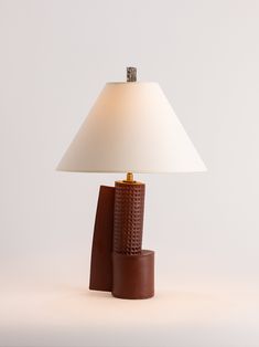 a lamp that is sitting on top of a wooden base with a white shade over it