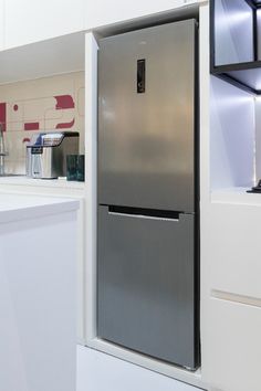 a stainless steel refrigerator in a kitchen with white counter tops and cabinets on the wall