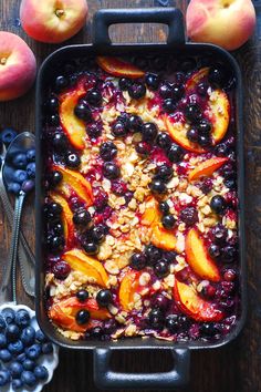 blueberries, peaches and granola in a casserole dish on a wooden table