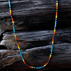 a multicolored beaded necklace is displayed on a piece of wooden planks