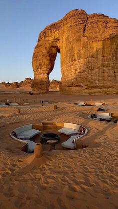 there are several boats in the sand near a rock formation