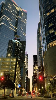 some very tall buildings in a big city at night with red traffic lights on the street