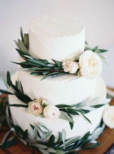 a white cake with flowers and greenery on top