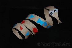 a snake made out of toilet paper on a black surface with red, white and blue tape