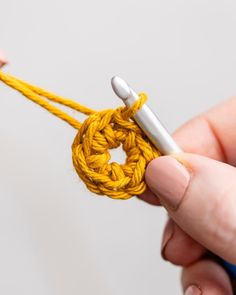 someone is crocheting the end of a piece of yellow yarn with a hook