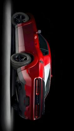 the front end of a red sports car with its hood up and wheels down, on a black background