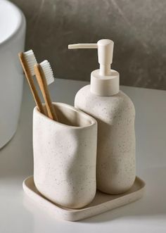 two toothbrushes and soap dispenser sitting on a counter