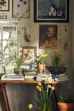 a table topped with lots of books and flowers next to a wall covered in pictures