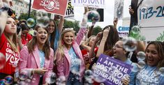 a group of women holding up signs and bubbles