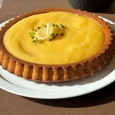 a pie on a white plate with a lemon garnish in the center and green sprinkles