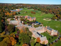 an aerial view of a large building in the middle of trees with fall foliage around it