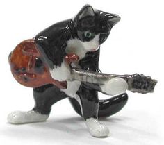 a black and white cat figurine with a guitar in it's paws