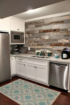 a kitchen with white cabinets and stainless steel appliances, along with a rug on the floor