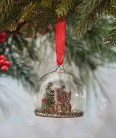 a glass ornament hanging from a christmas tree with a deer decoration on it