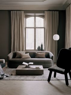 a living room with a couch, chair and table next to a window in black and white