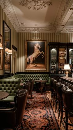 a room with green couches and paintings on the wall above them, along with chairs