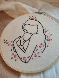 a cross stitched picture of a woman holding a baby in her arms with pink flowers on it