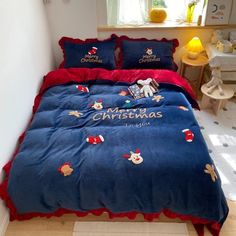 a blue comforter with red trim and christmas decorations on it in a white room